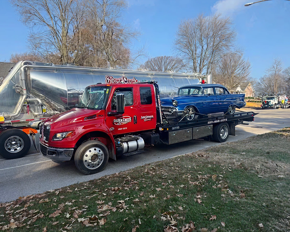 Red tow truck carrying vintage blue car